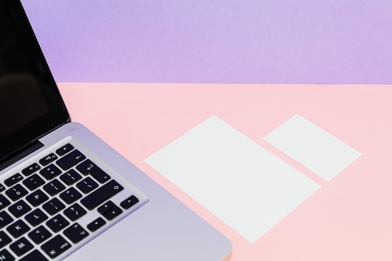 The Art of Drawing Readers In: Your attractive post title goes here Flat lay of a laptop with blank cards on a pastel pink and purple background, perfect for mockups.